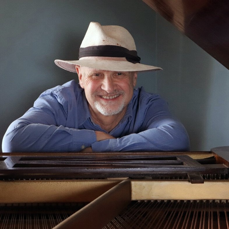 Richard smiling over the open piano in 2025